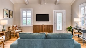 Uma sala de estar com um sofá grande cor de verde-água, um armário de madeira e uma televisão de tela plana fixada na parede.