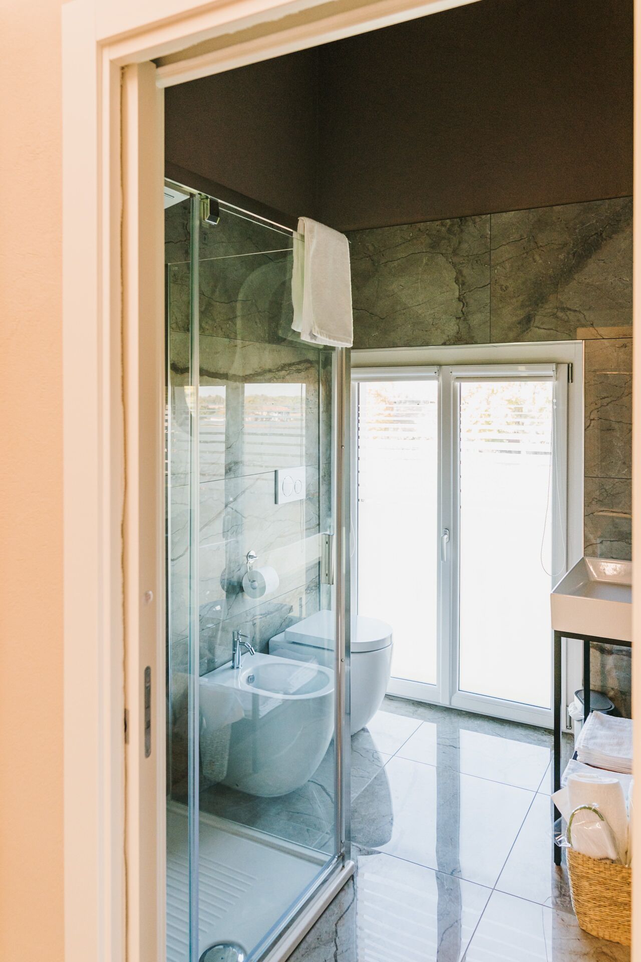 A modern bathroom with a glass-enclosed shower, a white sink, and a toilet.