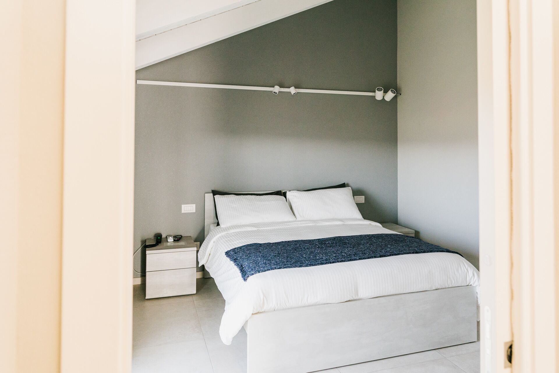 A bedroom with a bed, nightstand, and a ceiling light fixture.