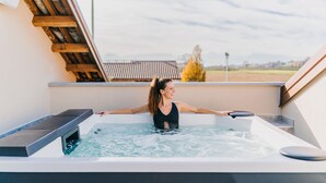 A person in a hot tub on a rooftop with a view of a residential area.