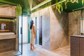 Een moderne badkamer met een glazen douchecabine, marmeren wanden en hangende beplanting.