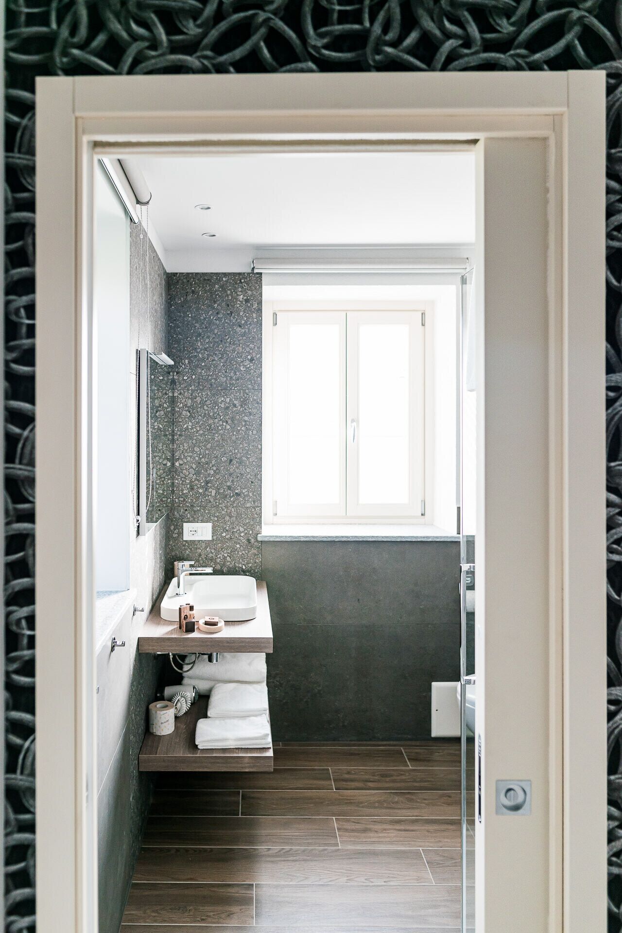 Een moderne badkamer met een ingebouwd wastafelmeubel, een spiegel en een raam boven de wastafel.