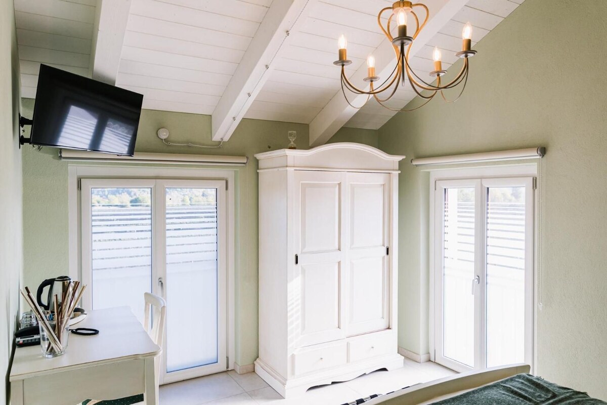 Une pièce avec une armoire blanche, un bureau avec une chaise et un téléviseur fixé au mur.