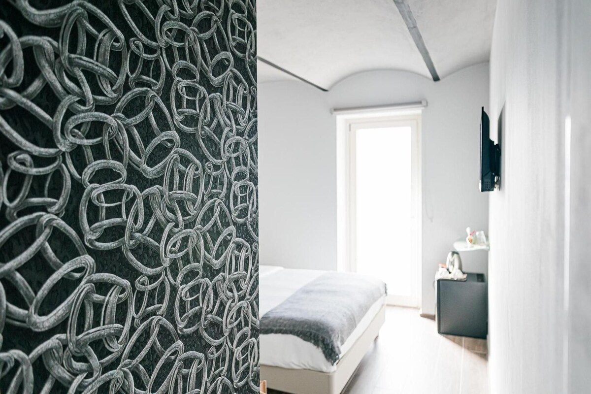 Ein modernes Schlafzimmer mit einem Bett, einem Nachttisch und einem großen Fenster.