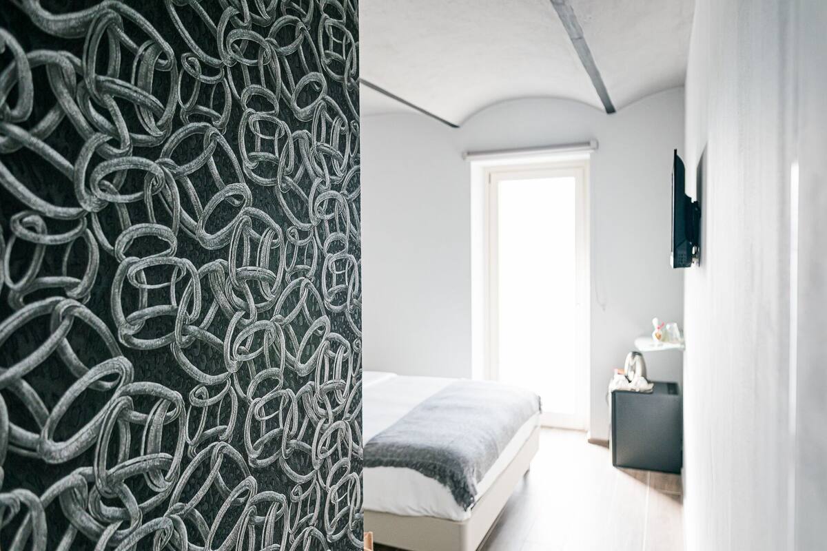 Ein modernes Schlafzimmer mit einem Bett, einem Nachttisch und einem großen Fenster.