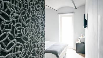 Un dormitorio moderno con cama, mesita de noche y un ventanal grande.
