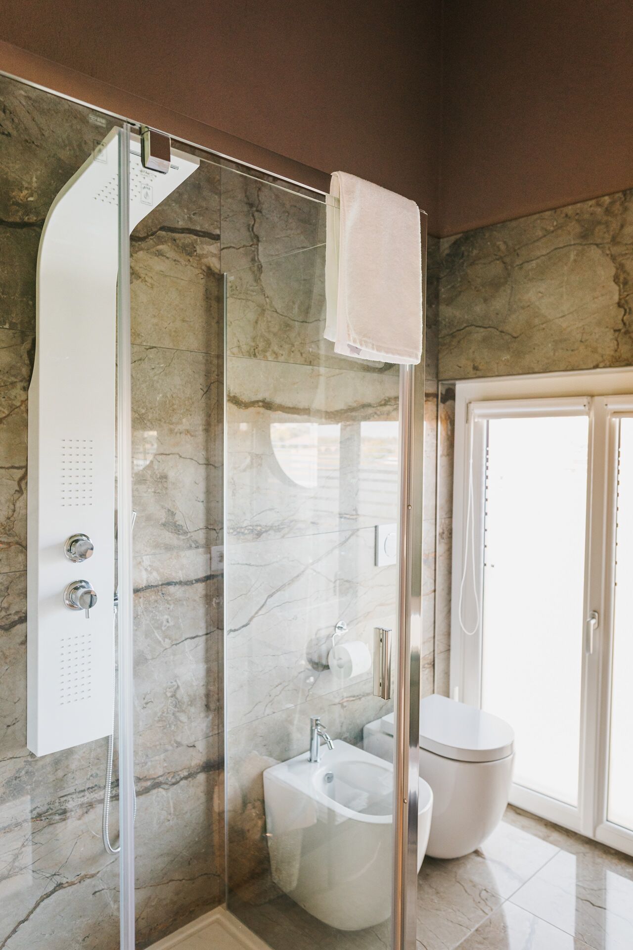 A modern bathroom with a glass-enclosed shower, a sink, and a toilet.