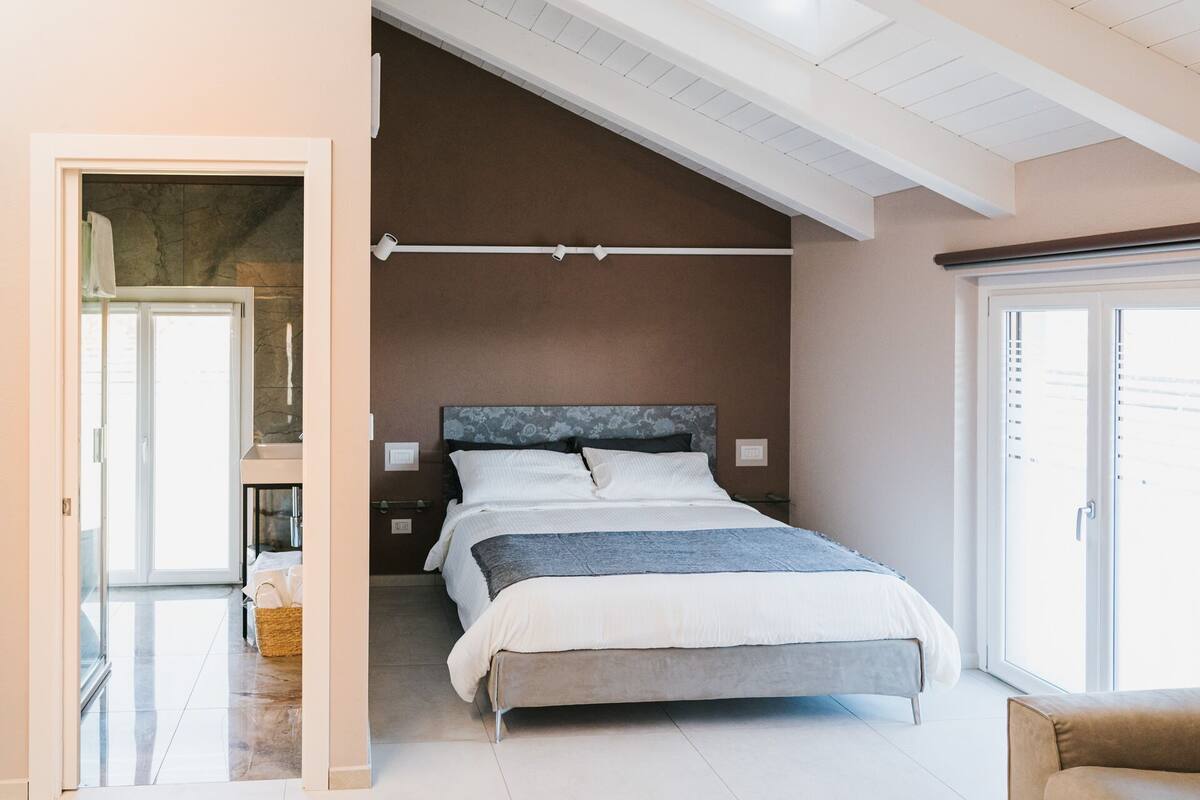 Ein Schlafzimmer mit Bett, Nachttisch, Fenster und Tür.