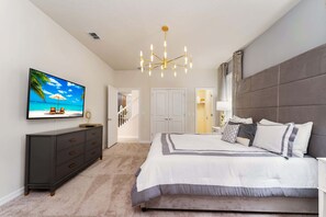 A bedroom with a large bed, a TV on a dresser, and a chandelier. - Luxurious 8BR Villa Retreat Themed Rooms & Pool (Davenport)