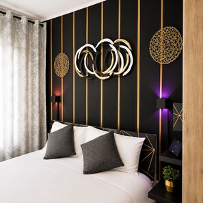 A modern bedroom with a bed, decorative wall art, and a nightstand with a plant.