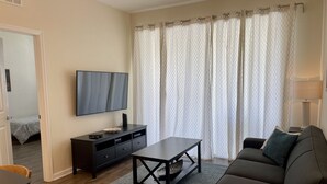 A living room with a sofa, a TV, a coffee table, and a TV stand. - Your Home in Orlando (Orlando)