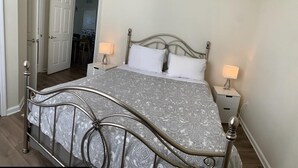 A bed with a metal frame, two bedside tables, and a patterned bedspread. - Your Home in Orlando (Orlando)