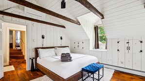 Un dormitorio con una cama de madera, paredes blancas y un ventanal grande.