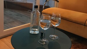 Una habitación con una mesa de vidrio, una botella y dos vasos de agua.