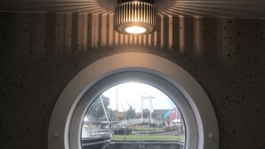 Una ventana redonda con vistas a barcos y un puente al fondo.