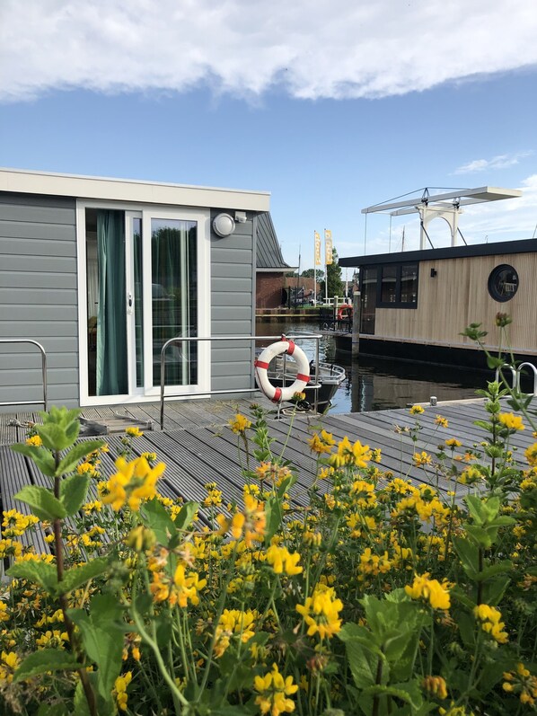 Exterior detail - Modern houseboat in quiet harbor close to the IJsselmeer with SUPs and canoe (Stavoren)