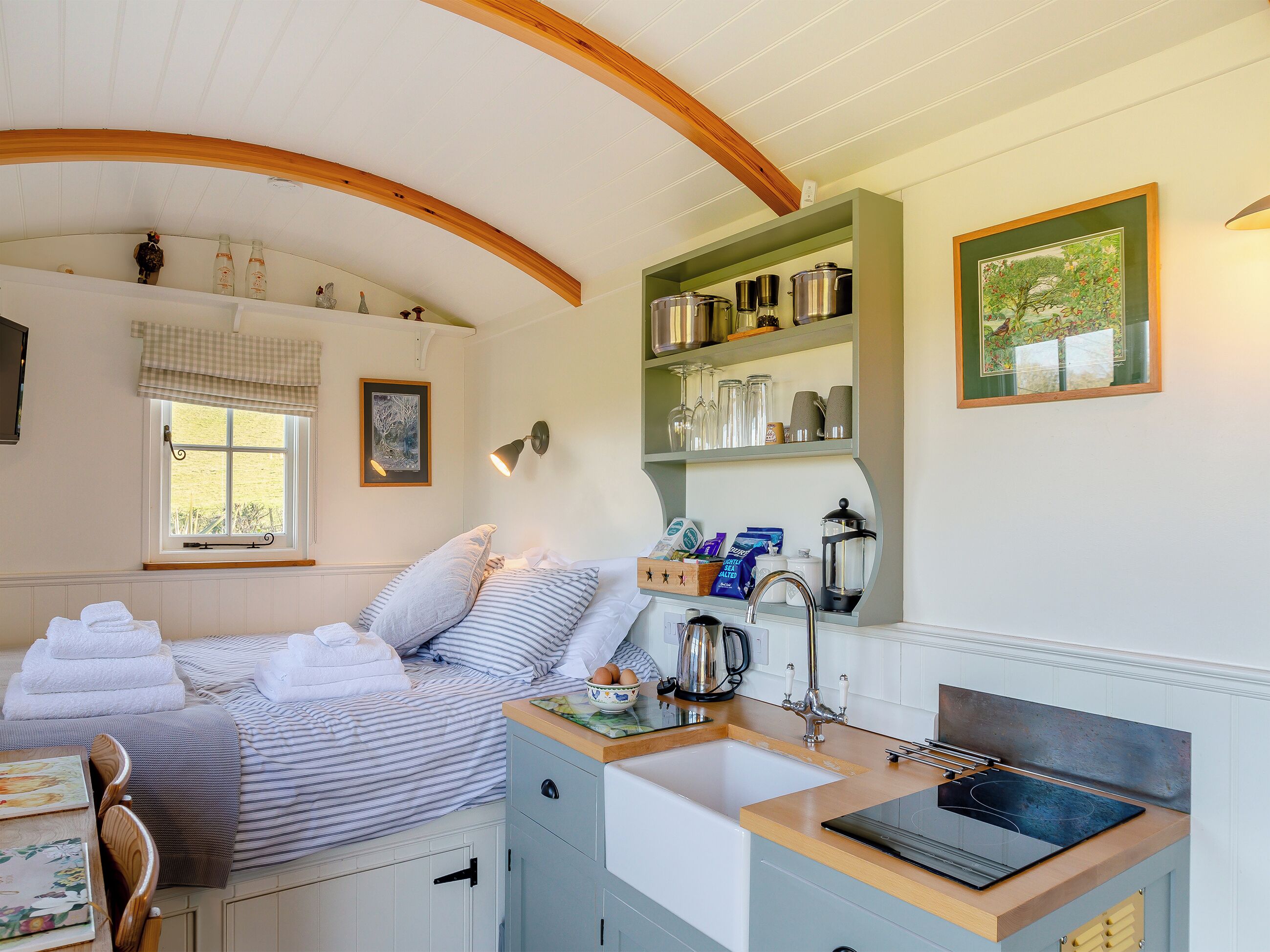 A bedroom with a bed, a bedside table, a window, and a view of the outdoors.