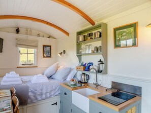 A bedroom with a bed, a bedside table, a window, and a view of the outdoors.