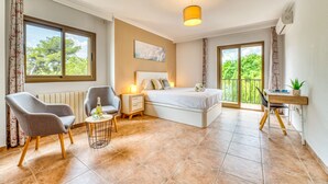 A modern bedroom with a bed, bedside table, chair, and a small table with a bottle and glasses. - House with pool Casa Jordi in Playa de Muro (Can Picafort)