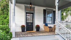 A white house with a black door, number 2319, a porch with wicker furniture, and a white railing. - Historic Charm | Near USC, Fort Jackson & 5 Points (Columbia)