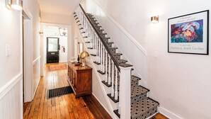 A staircase with a patterned carpet, a wooden console table with a lamp, and a framed picture on the wall. - Historic Charm | Near USC, Fort Jackson & 5 Points (Columbia)