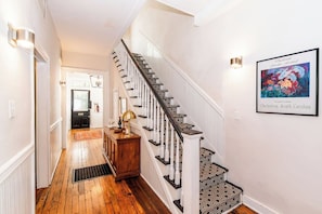 A staircase with a patterned carpet, a wooden console table with a lamp, and a framed picture on the wall.