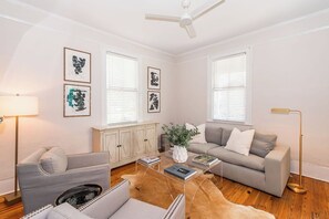 A living room with a sofa, a coffee table, a lamp, and artwork on the walls.