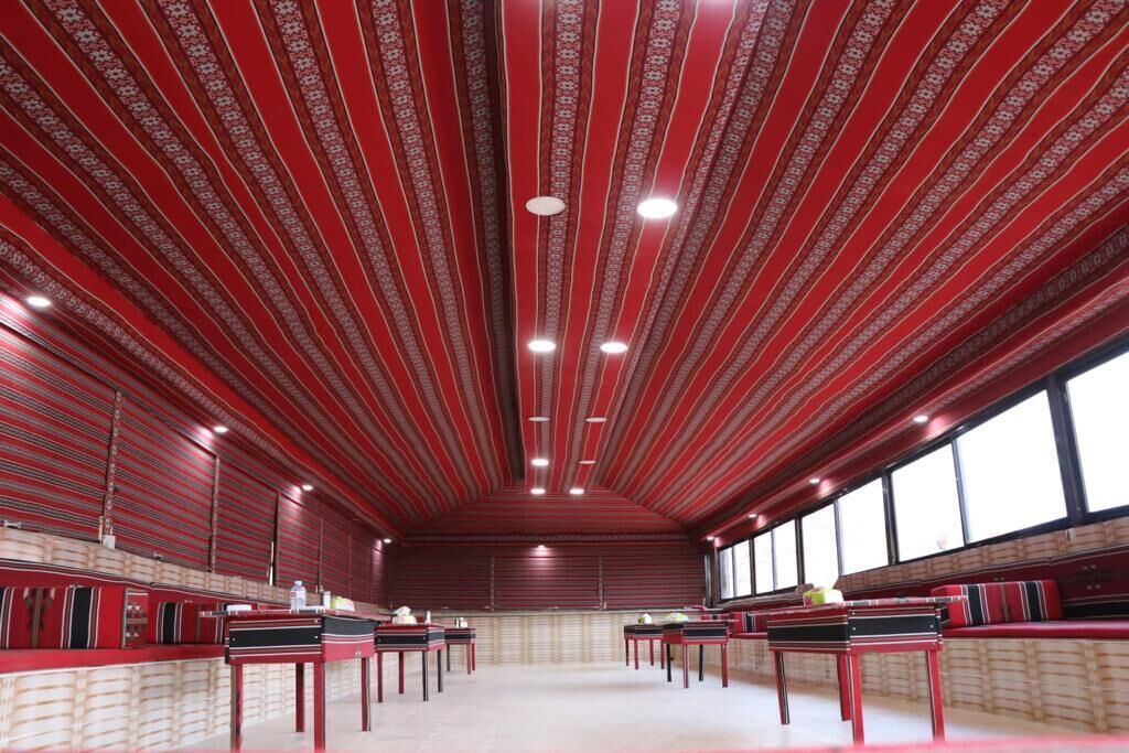 A room with striped red ceiling, multiple tables, and large windows.