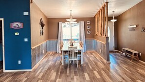 A dining area with a wooden table and chairs, a chandelier, and a view through a window. - Your home away from home mountain cabin (Bayfield)