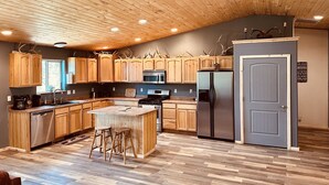 A modern kitchen with wooden cabinets, a central island, and a built-in refrigerator. - Your home away from home mountain cabin (Bayfield)