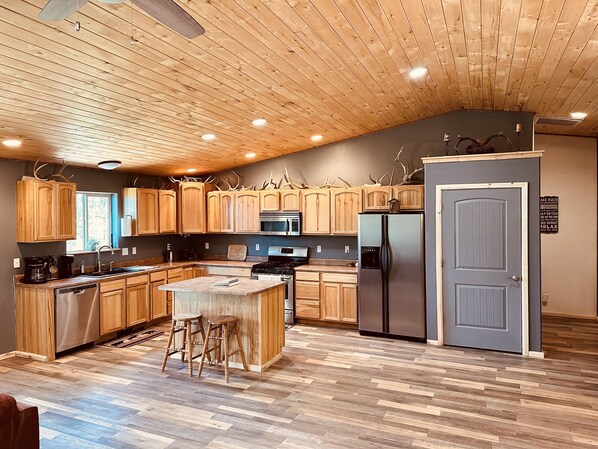 Une cuisine moderne avec des meubles en bois, un îlot central et un réfrigérateur encastré.