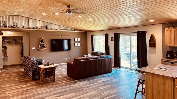 A spacious living area with a wooden ceiling, a large flat-screen TV, a sofa, and a dining table. - Your home away from home mountain cabin (Bayfield)