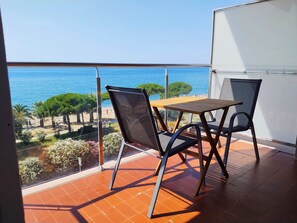 Ein Balkon mit Tisch und Stühlen mit Blick auf einen Strand und das Meer.