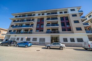 Ein mehrstöckiges Wohnhaus mit Balkonen, einem verschlossenen Eingang und geparkten Autos.