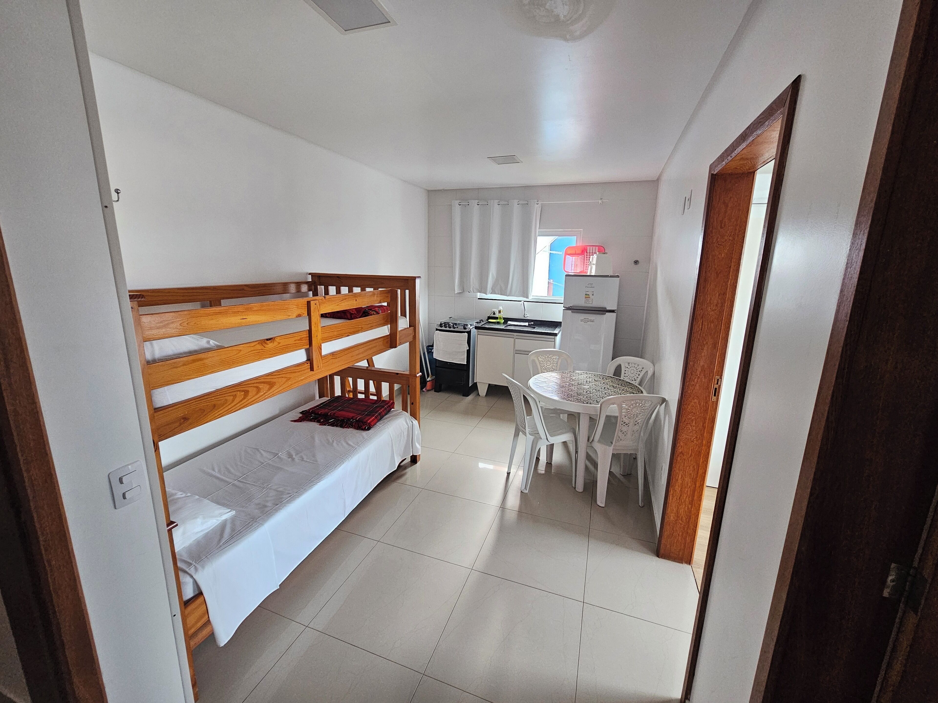 A small, clean room with a bunk bed, a kitchenette, and a dining area.