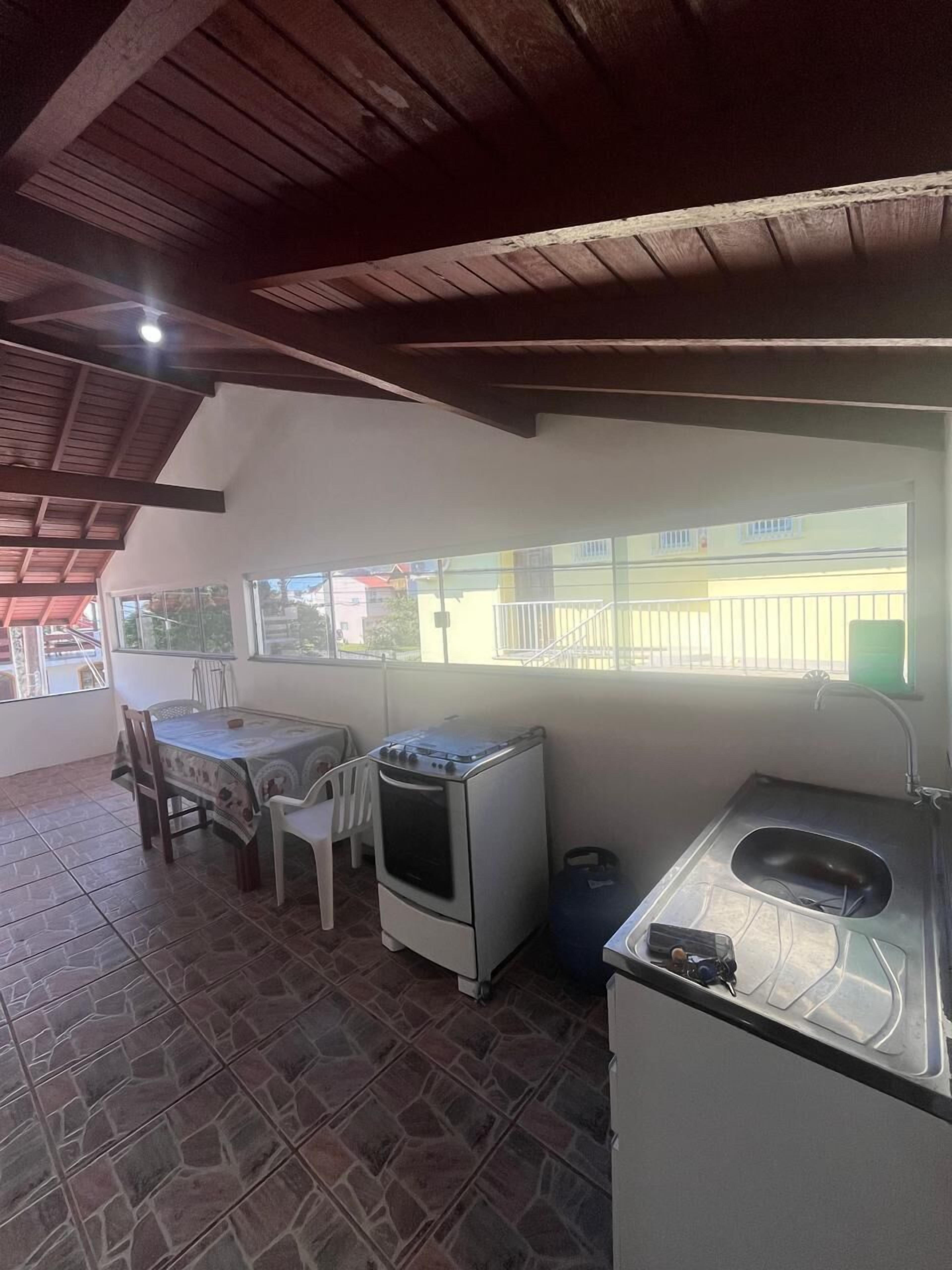 Una cocina compacta con estufa a gas, un lavamanos y una zona de comedor con mesa y sillas.