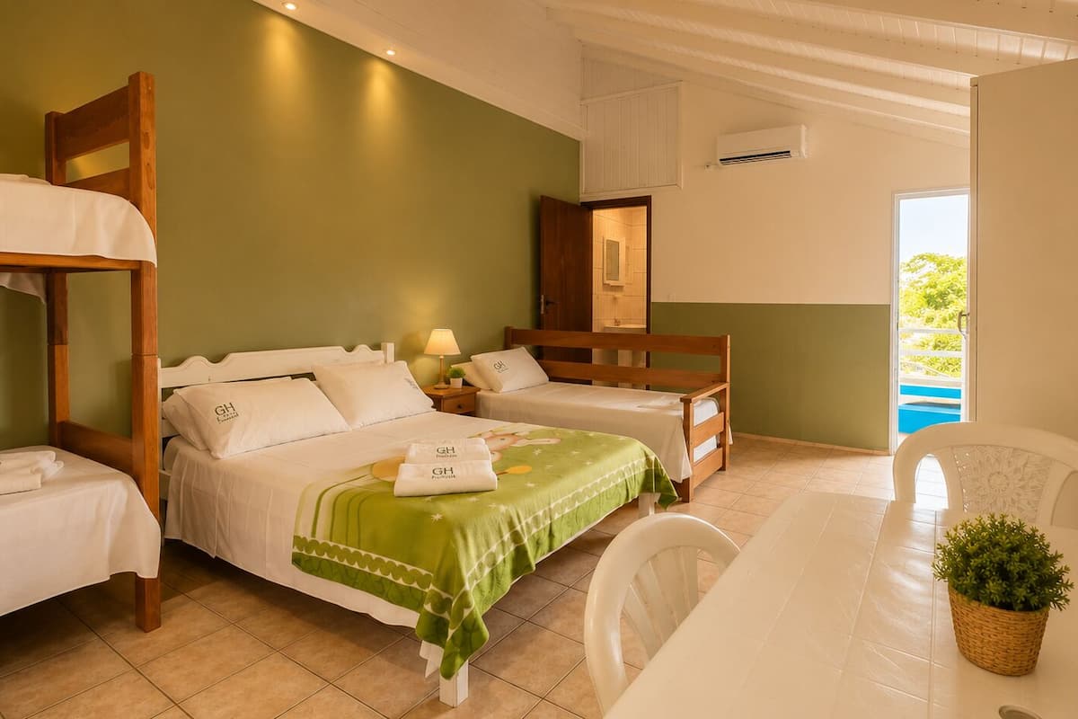 A hotel room with two single beds, a wooden headboard, a small table with a plant, and a view of a pool.
