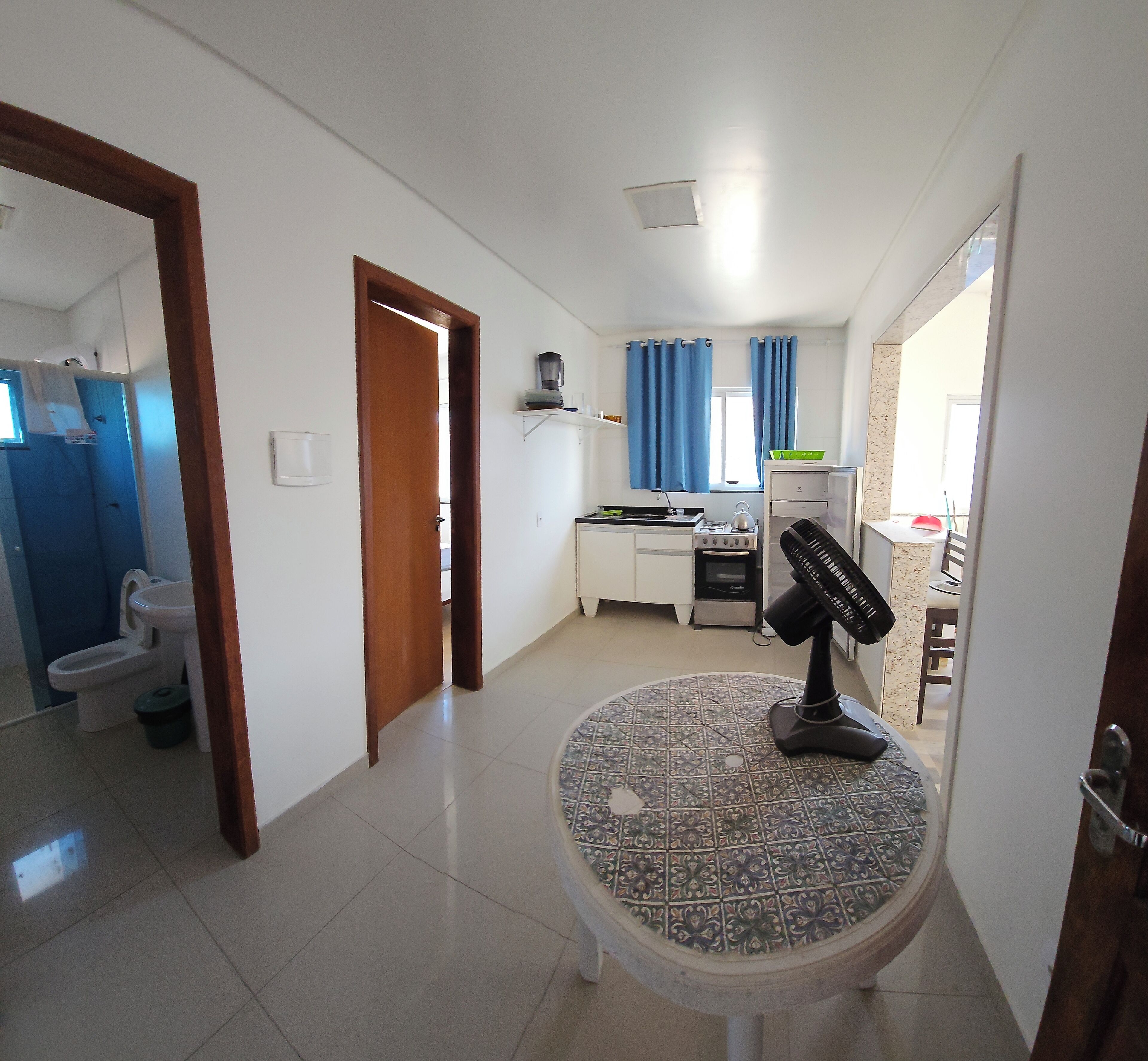 A modern kitchen with a gas stove, a kettle, and a coffee maker. There is a small dining table with a chair.