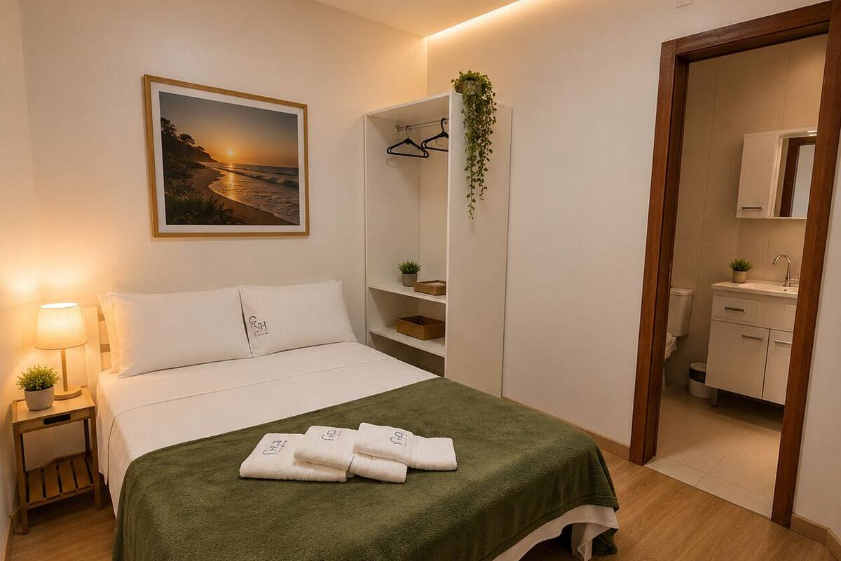 A neatly arranged bedroom with a bed, bedside lamp, and a painting on the wall.