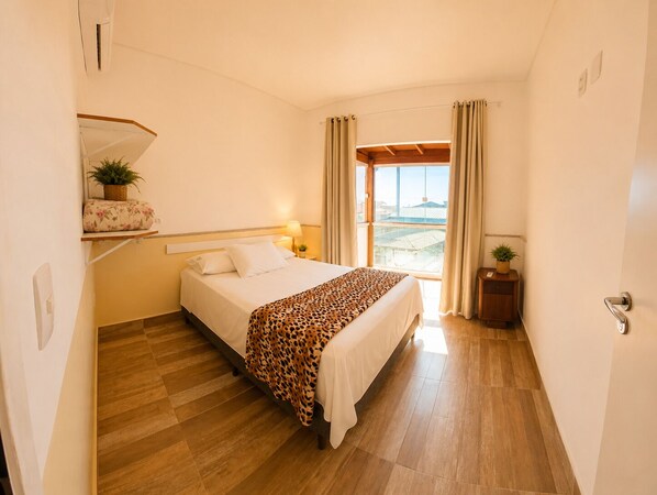 A hotel room with a bed, a nightstand, a window with curtains, and a view of the outside. - GH Barra da Lagoa (Florianópolis)