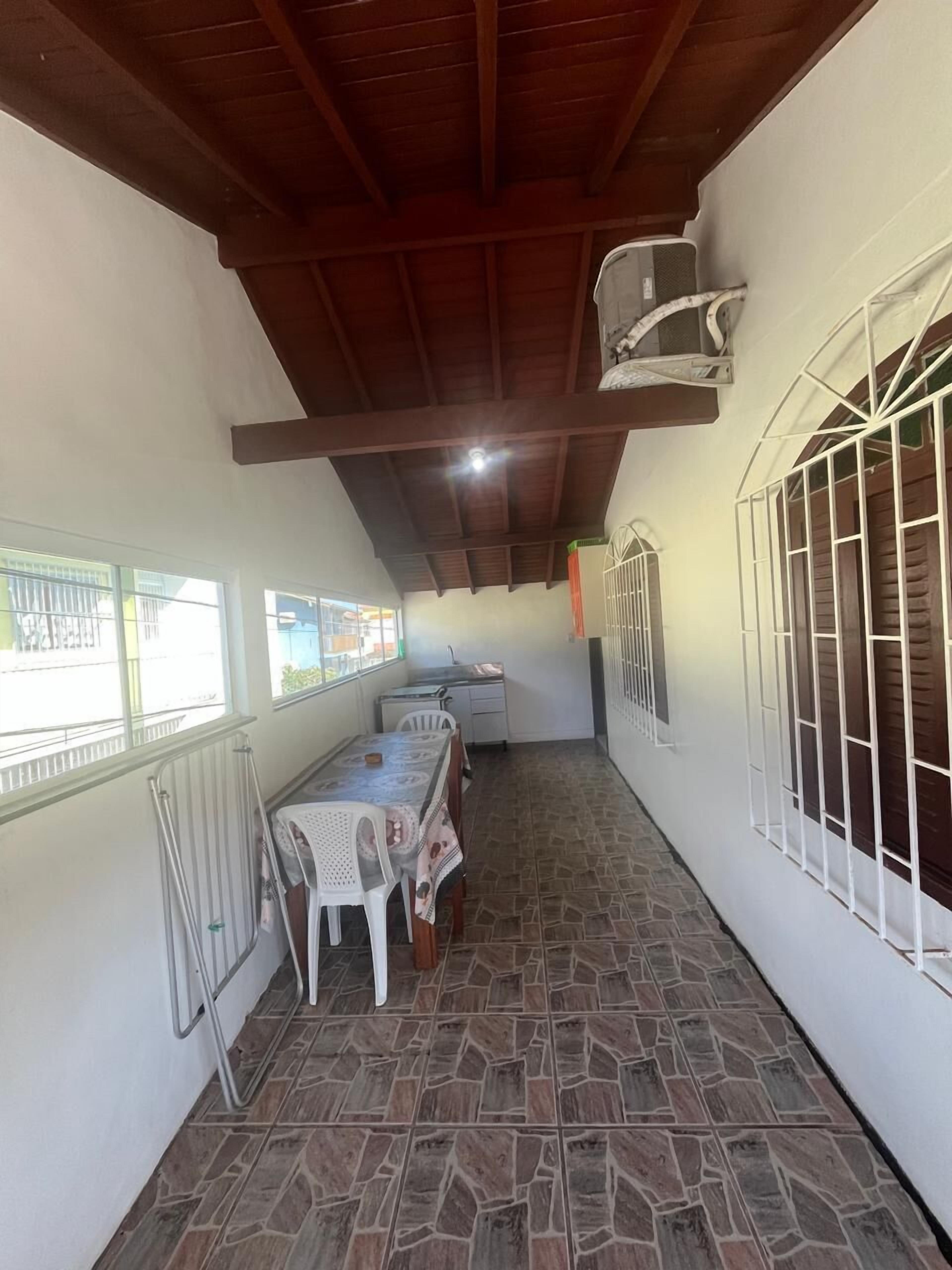 A narrow corridor with a tiled floor, a table with chairs, a radiator, and a window with bars.