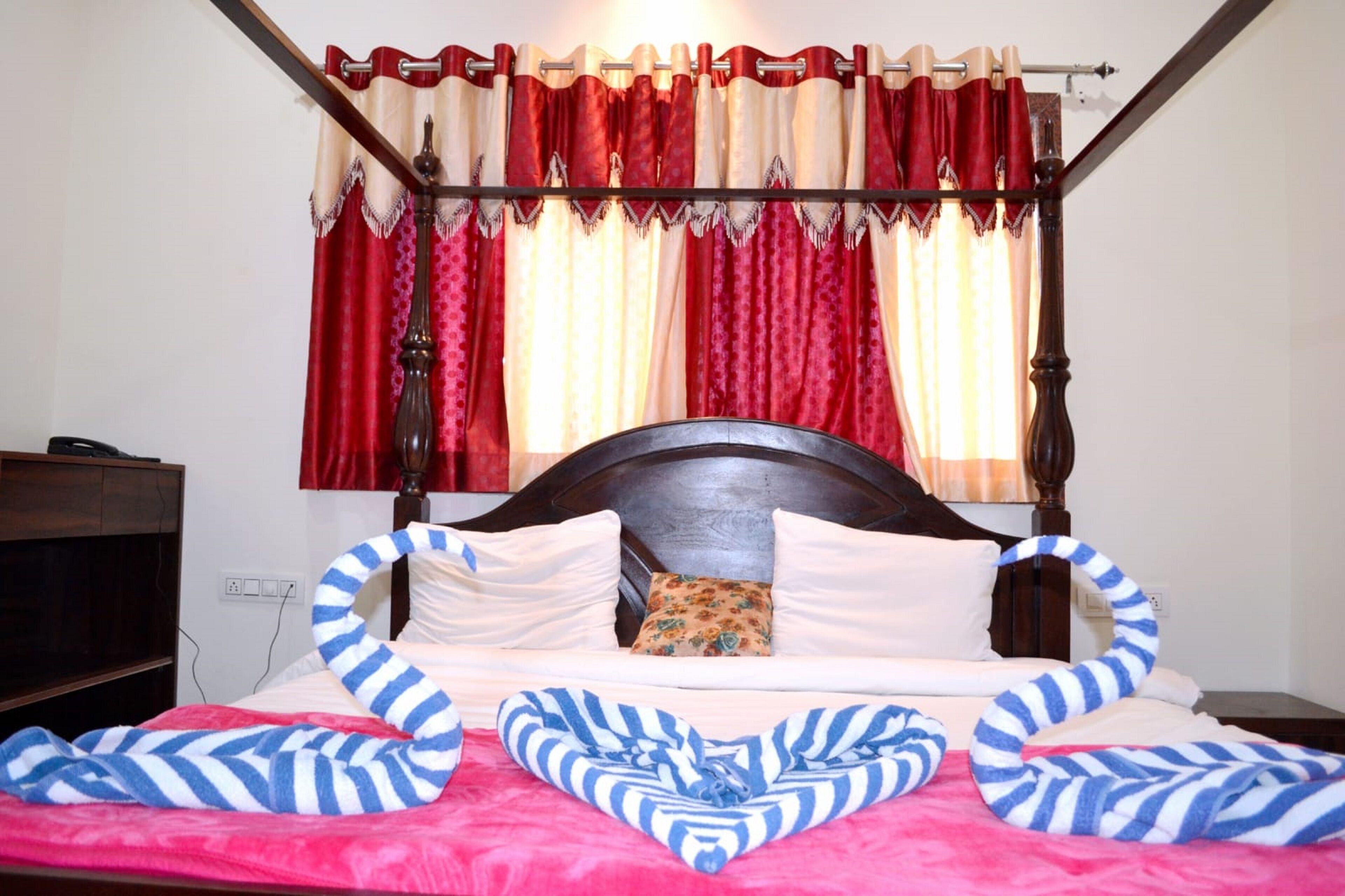 A bed with striped pillows, a wooden headboard, and red curtains.