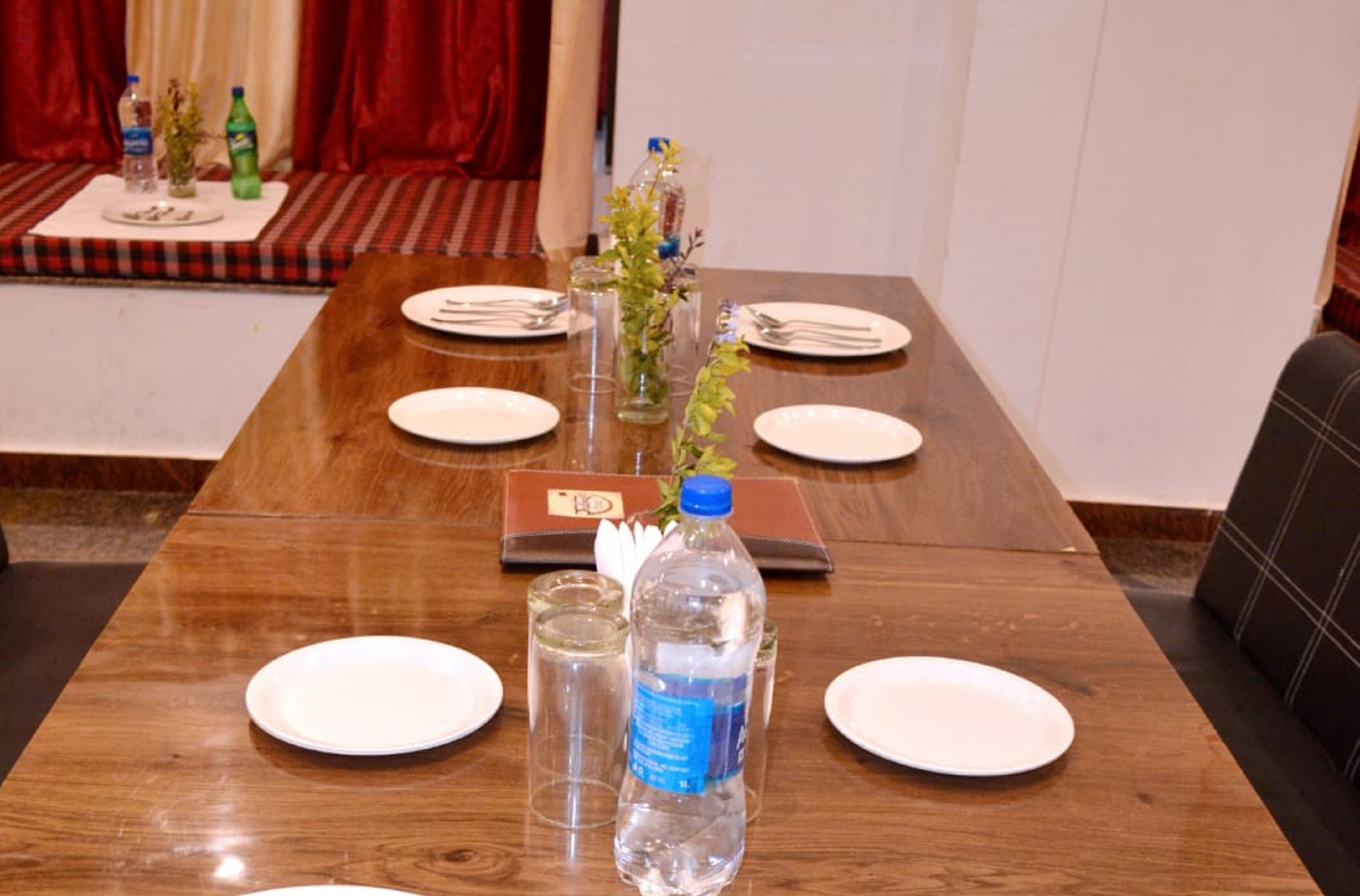 A conference table with white plates, water bottles, and a vase with flowers.
