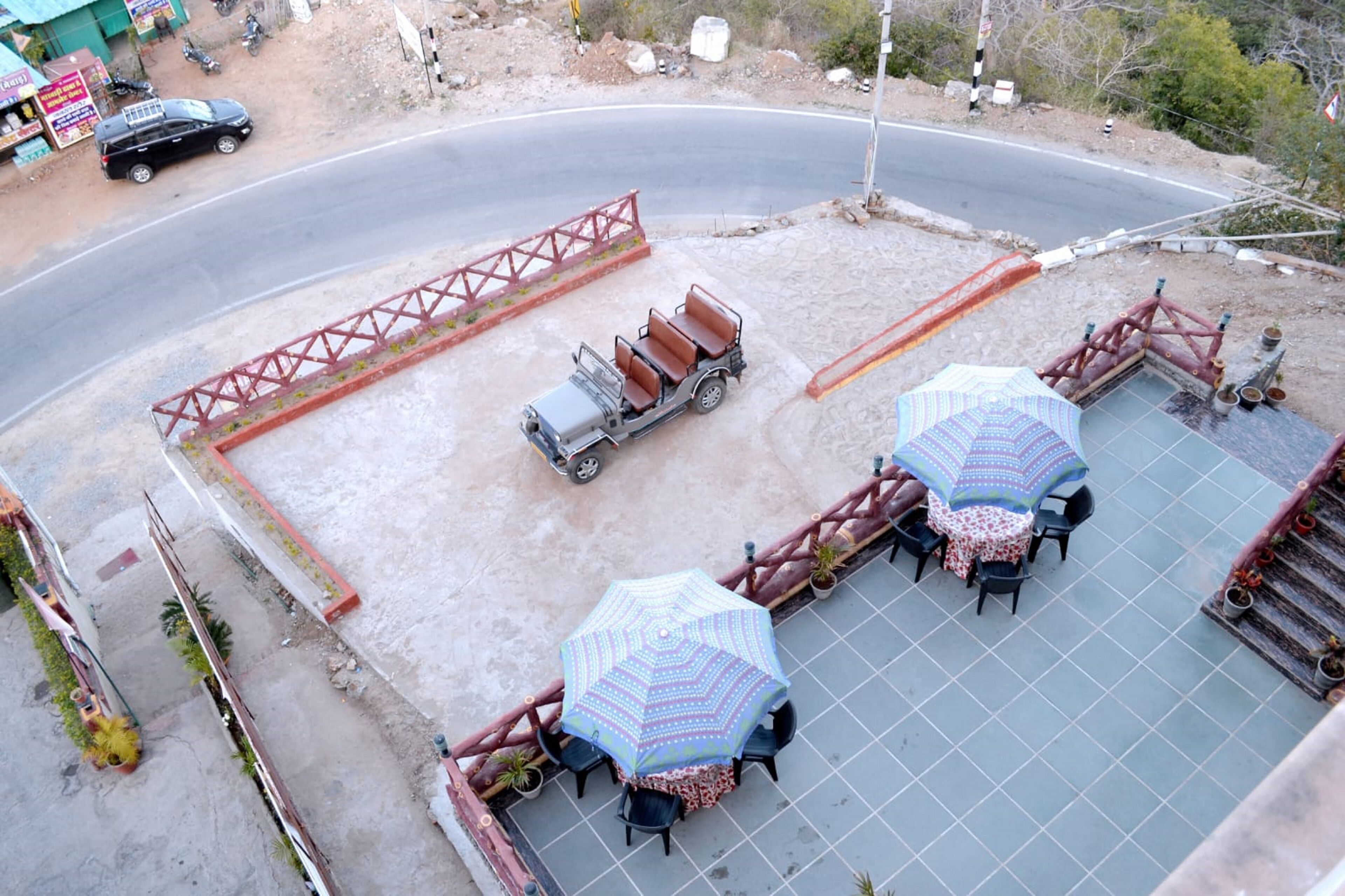 Een terras met tafels en parasols, een kleine vrachtwagen en een rode reling.