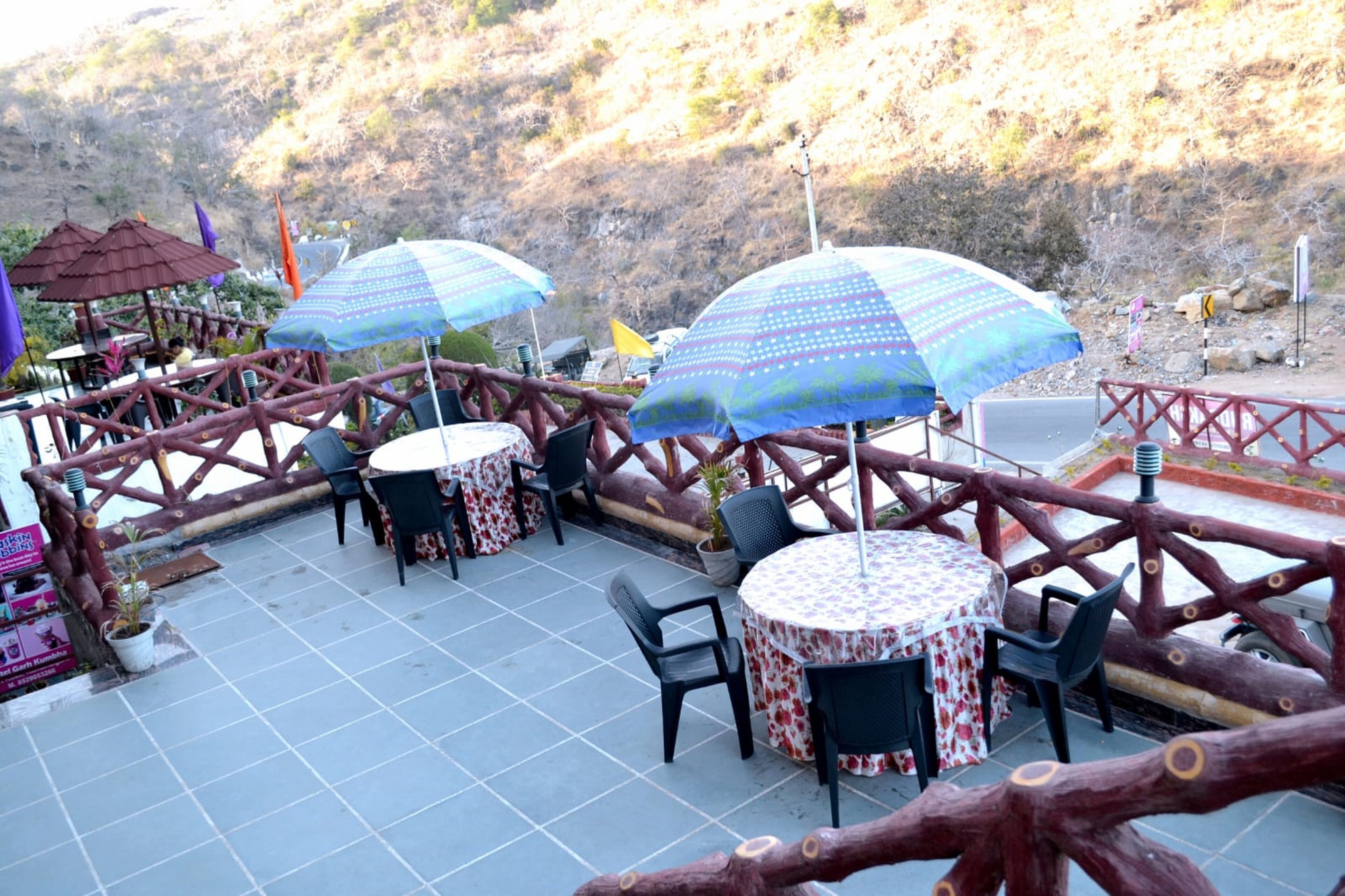 An outdoor patio with tables and chairs, umbrellas, and a wooden fence.