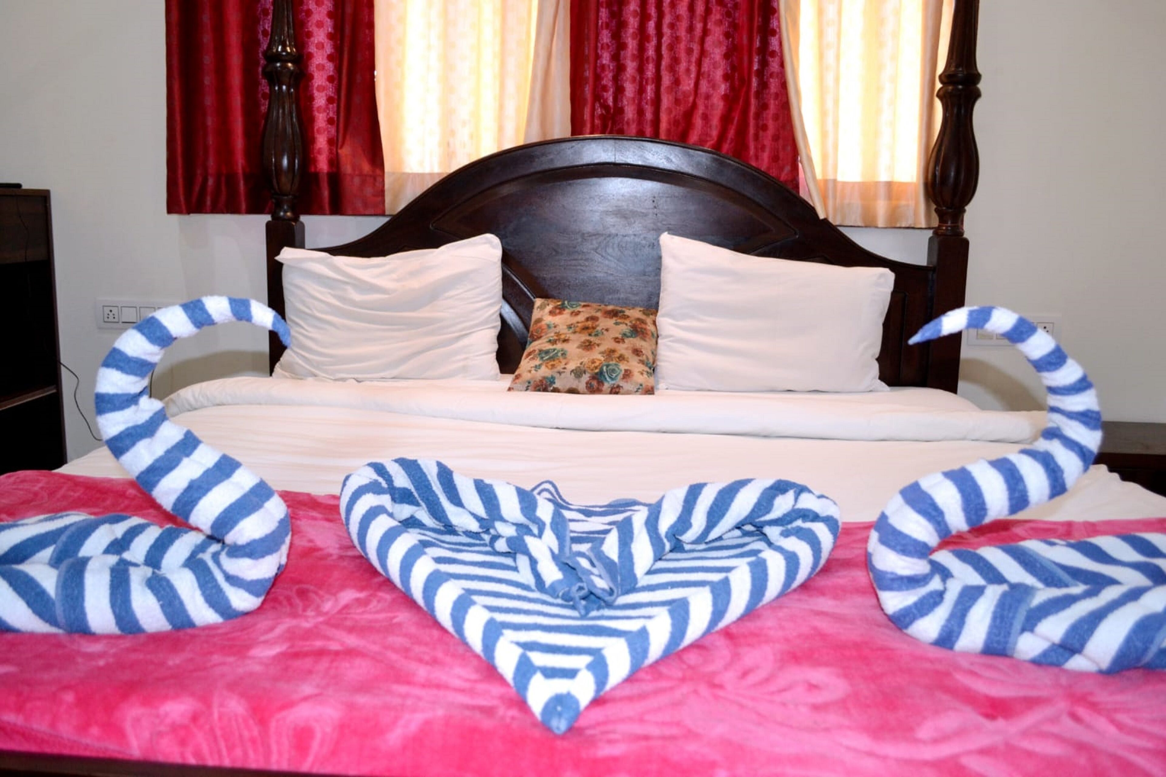 A bed with a wooden headboard, white pillows, and a floral pillow. There are striped pillows on either side of the bed.
