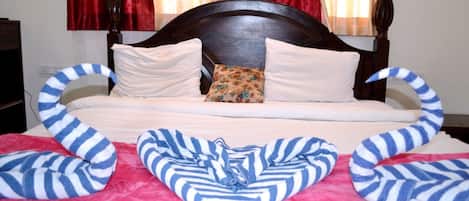 A bed with a wooden headboard, white pillows, and a floral pillow. There are striped pillows on either side of the bed.