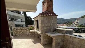 Una cocina al aire libre de piedra con chimenea, paredes de piedra y un patio con baldosas.