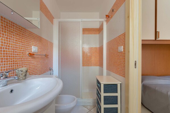 Un baño con lavamanos blanco, inodoro y cabina de ducha.