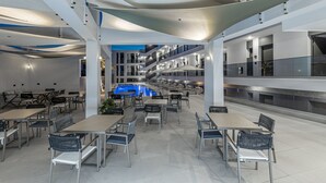 Un comedor moderno en el interior con mesas y sillas, una piscina y una escalera que sube a niveles superiores.